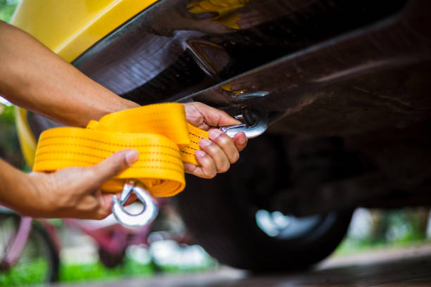Hands of man holding yellow car towing strap with yellow car. Yellow car towing. towing rope.